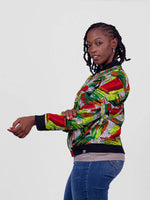 A woman wearing a green and black Kitenge bomber jacket with a front zipper.